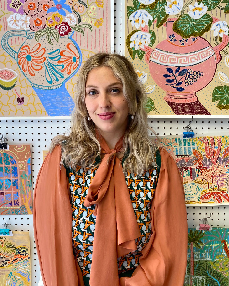 UK-based artist Camilla Perkins standing in front of artworks from her ...